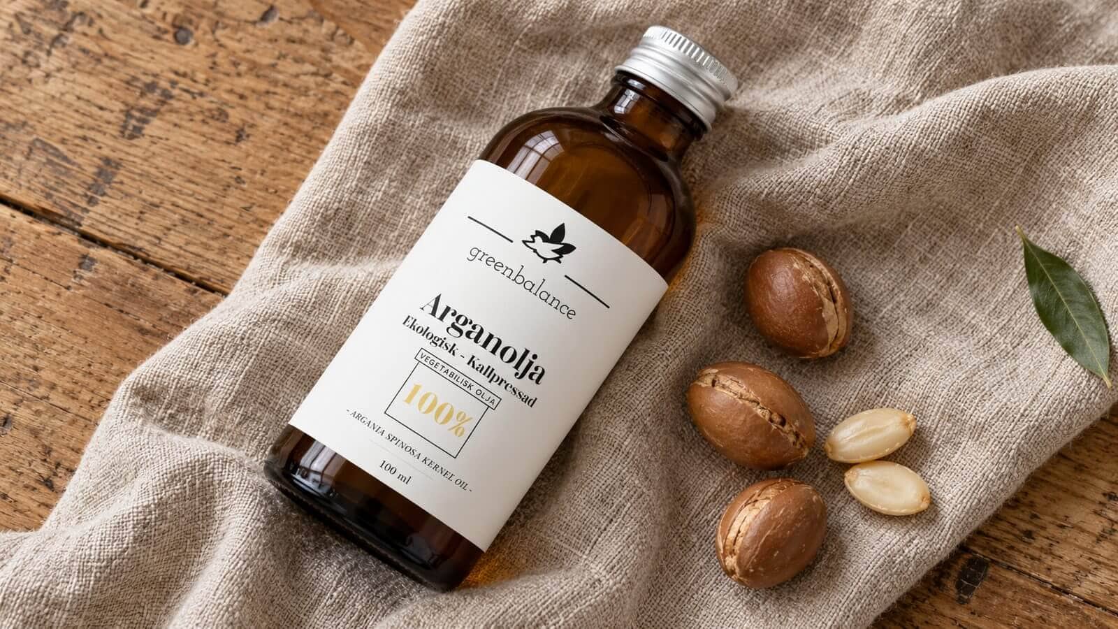 arganolja produkt ravaror Flaska med arganolja liggande på linne och trä, med argannötter och kärnor.
