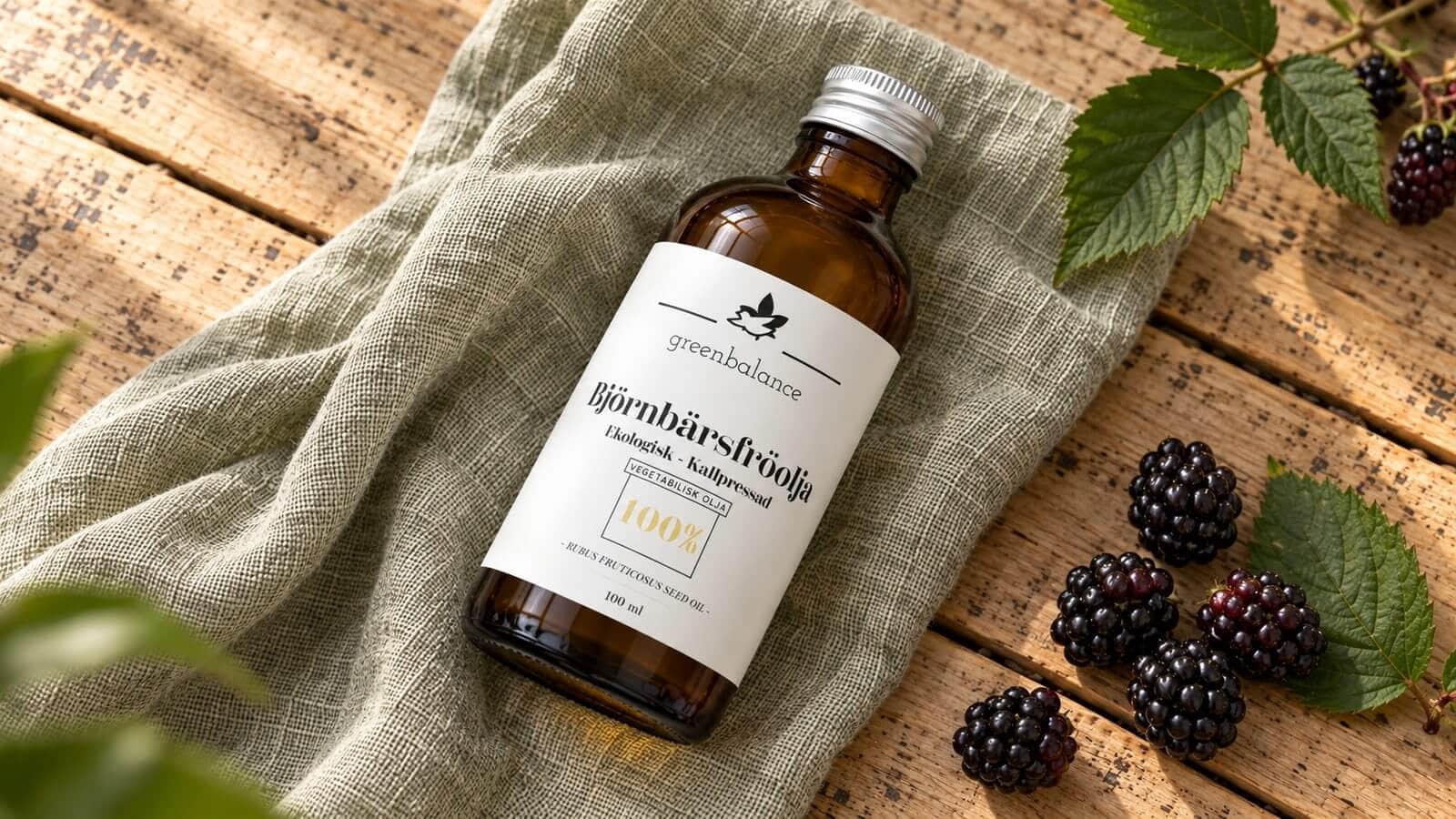 bjornbarsfroolja produkt ravaror Flaska med björnbärsfröolja liggande på linne och trä, med björnbär och blad.