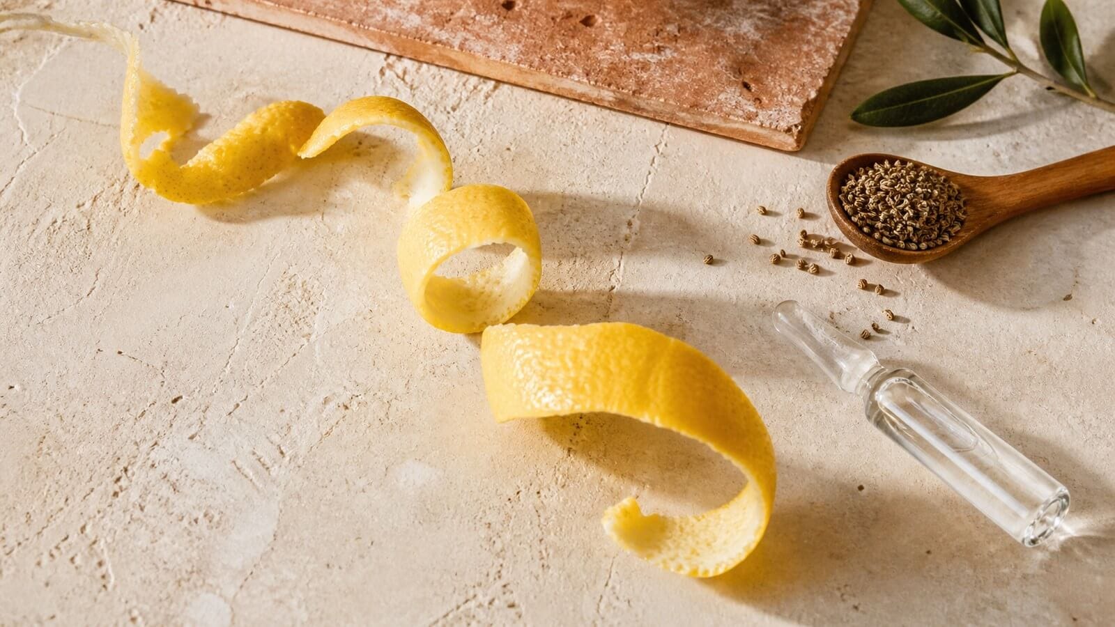 gamma-terpinen-citrus-krydda Citronskal, kryddfrön och en klar glasampull på varm sten.