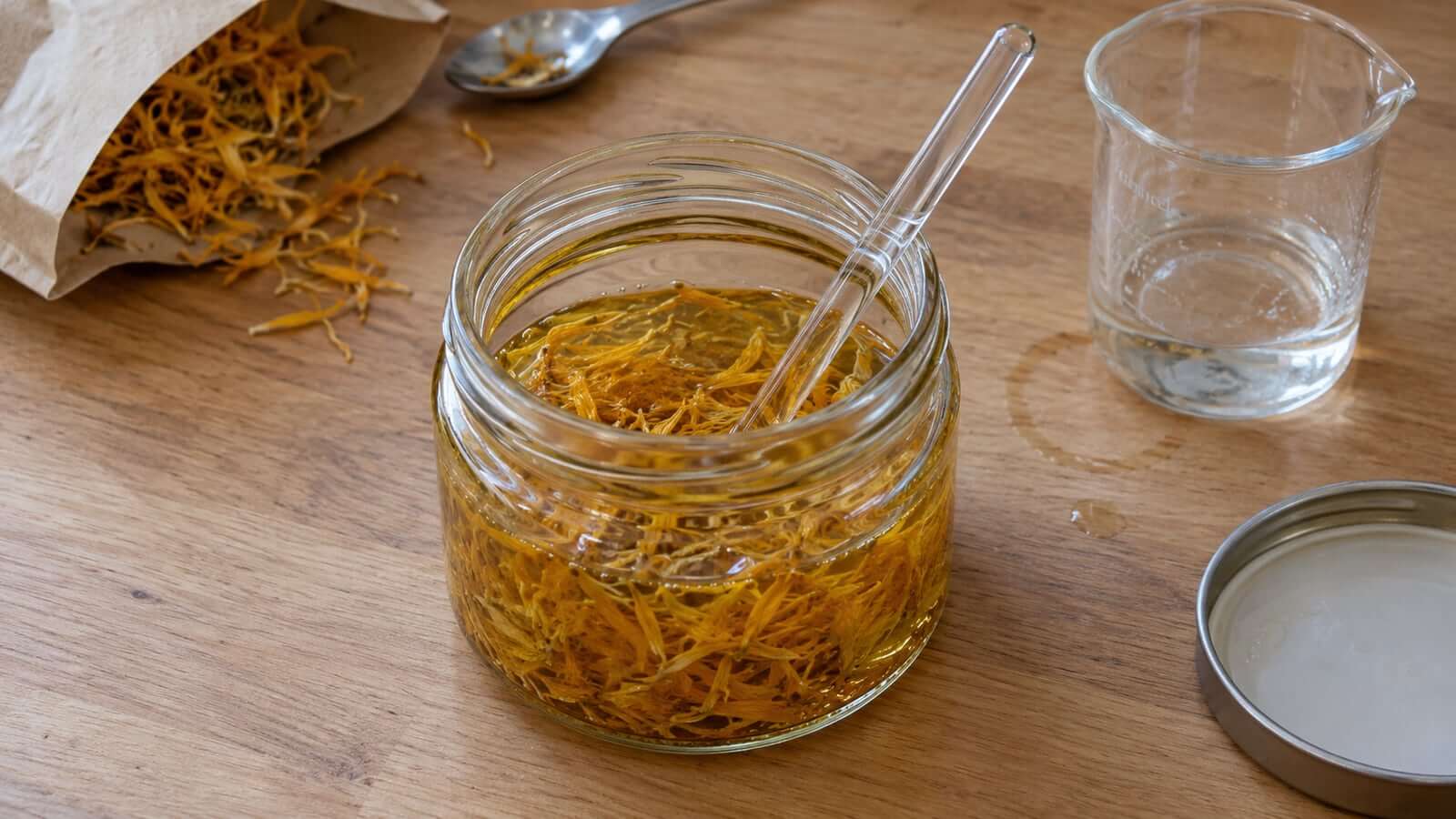 glycerit genomfuktning Små ringblomskronblad genomfuktas i en glasburk med en omrörningsstav och blandningskärl intill