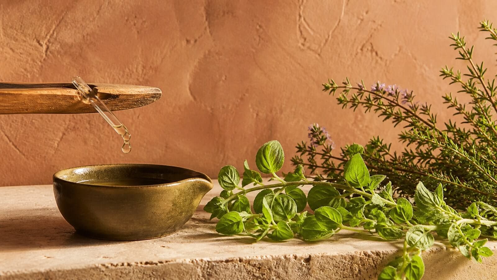 karvakrol-oregano-timjan Oregano, timjan och en klar droppe över en mörkgrön keramikkopp.
