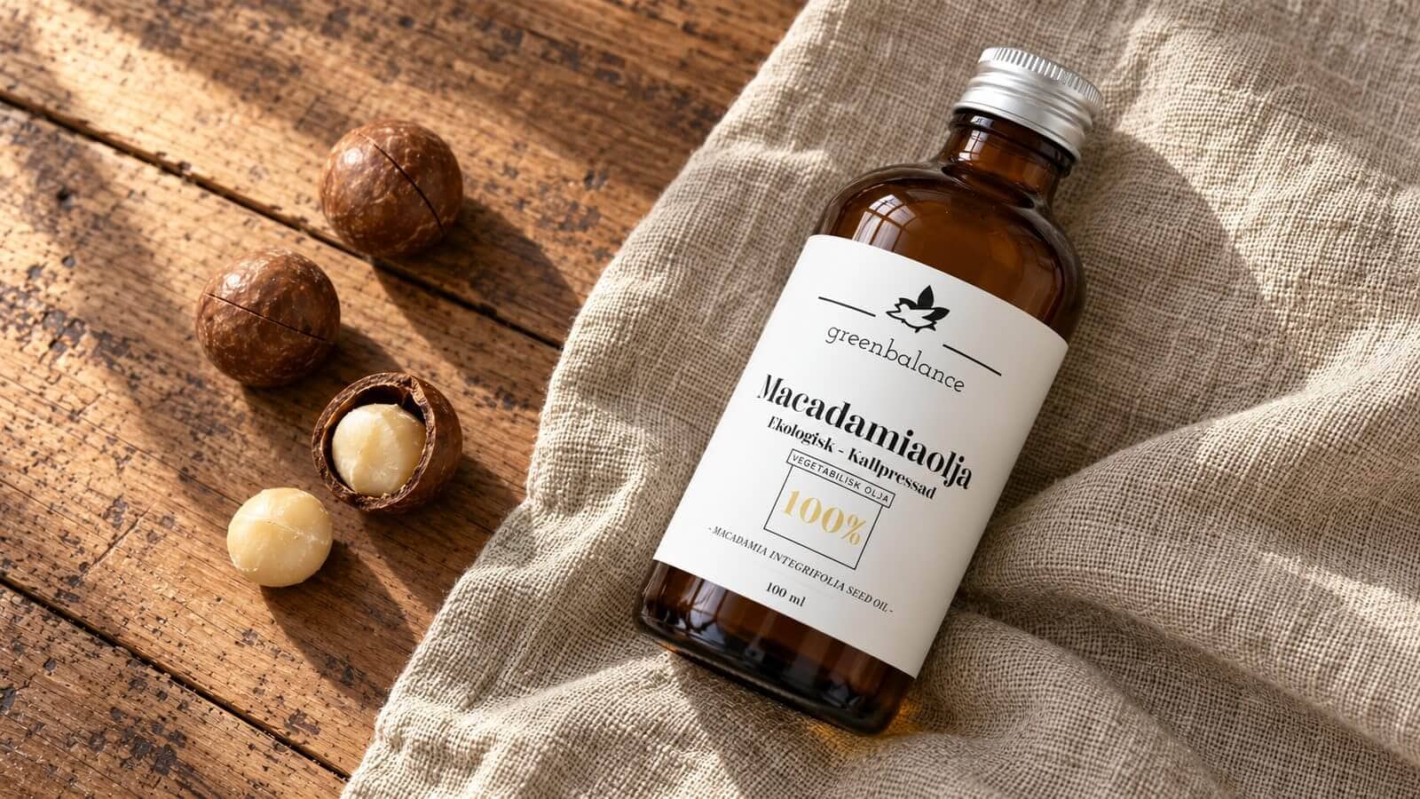 macadamiaolja produkt ravaror Flaska med macadamiaolja liggande på linne och trä, med macadamianötter och kärnor.