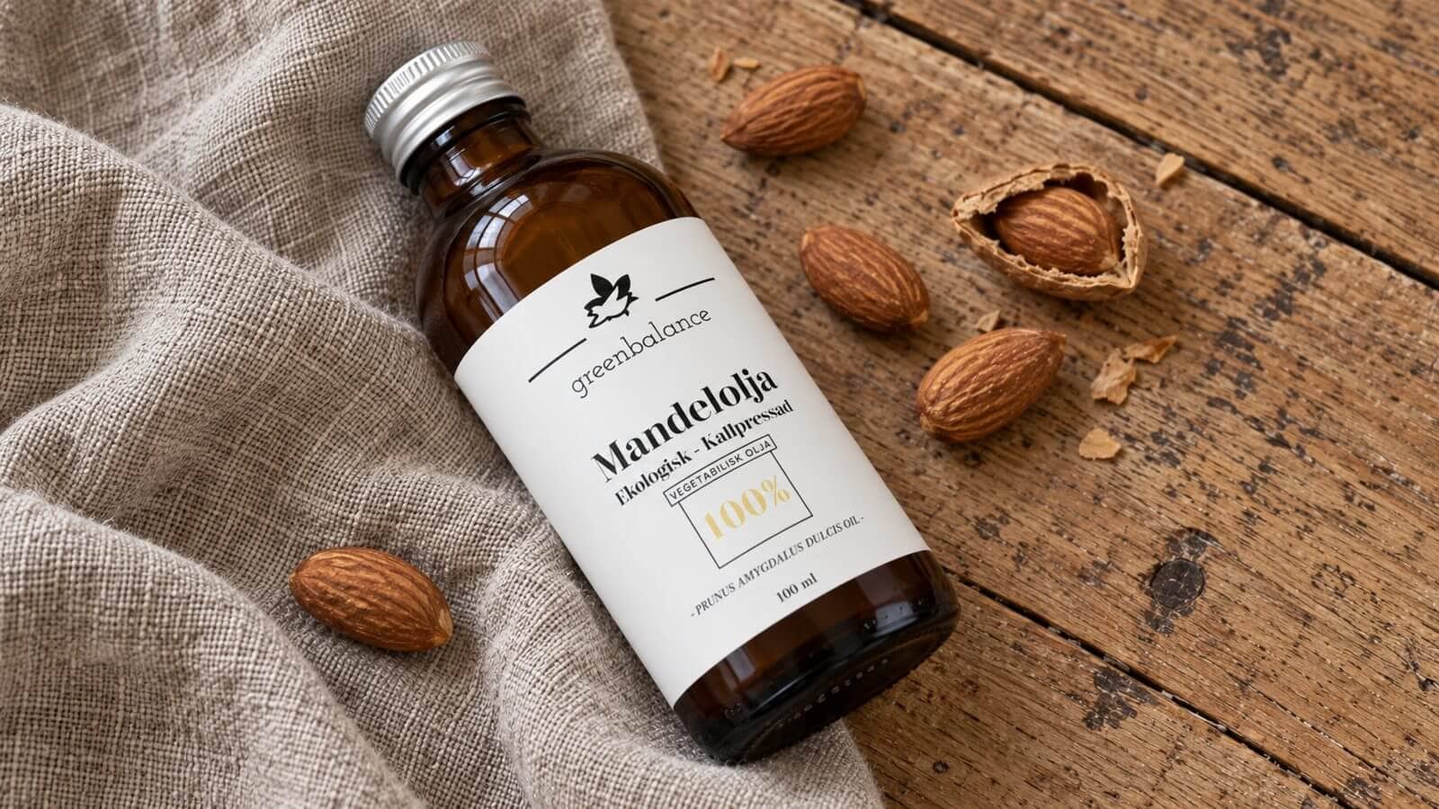 mandelolja produkt ravaror Flaska med mandelolja liggande på linne och trä, med mandlar och mandelskal.